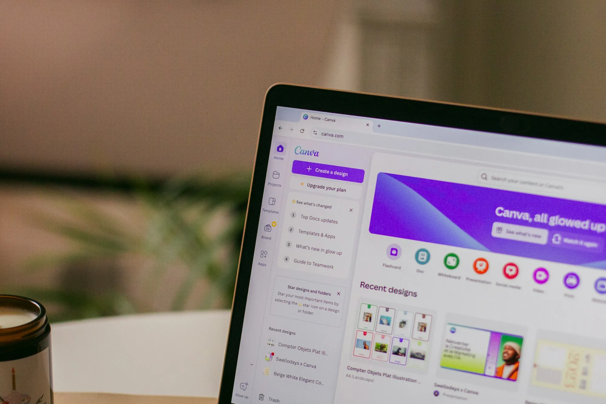 A laptop on a wooden desk with the Canva design tool open in the browser